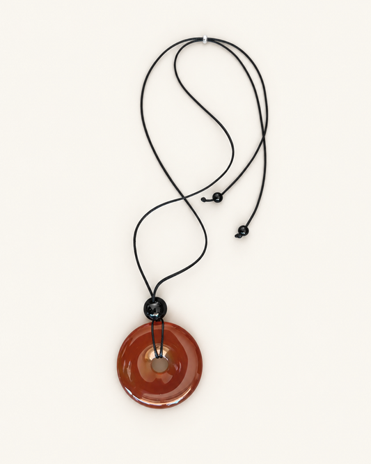 Necklace with a brown circular pendant on a light white background