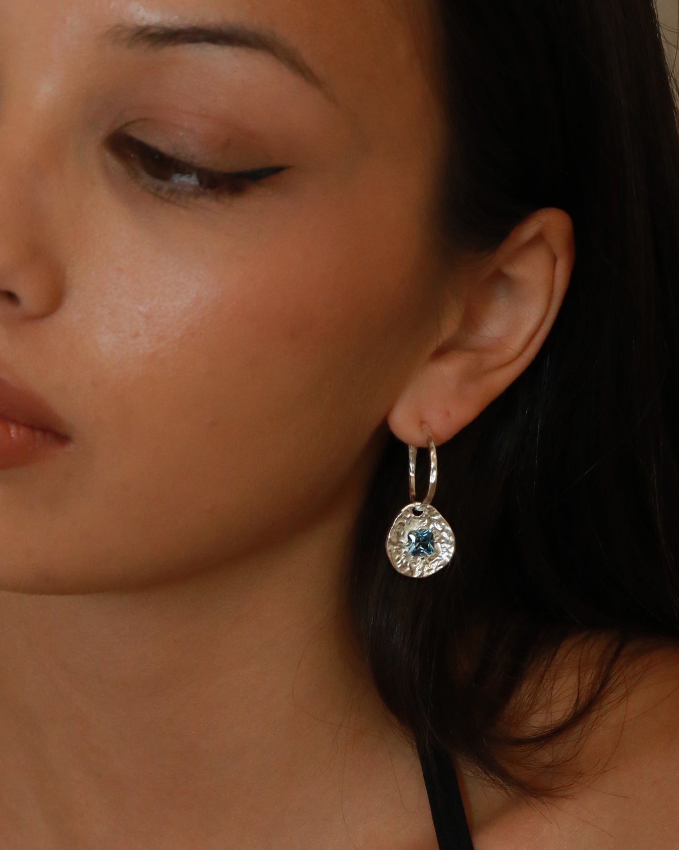 Cleo silver-plated brass coin drop earrings with hammered texture and square blue tourmaline CZ stones on a model