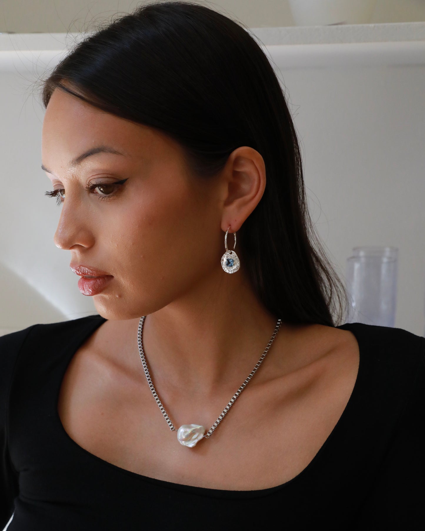 Cleo silver-plated brass coin drop earrings with hammered texture and square blue tourmaline CZ stones on a model
