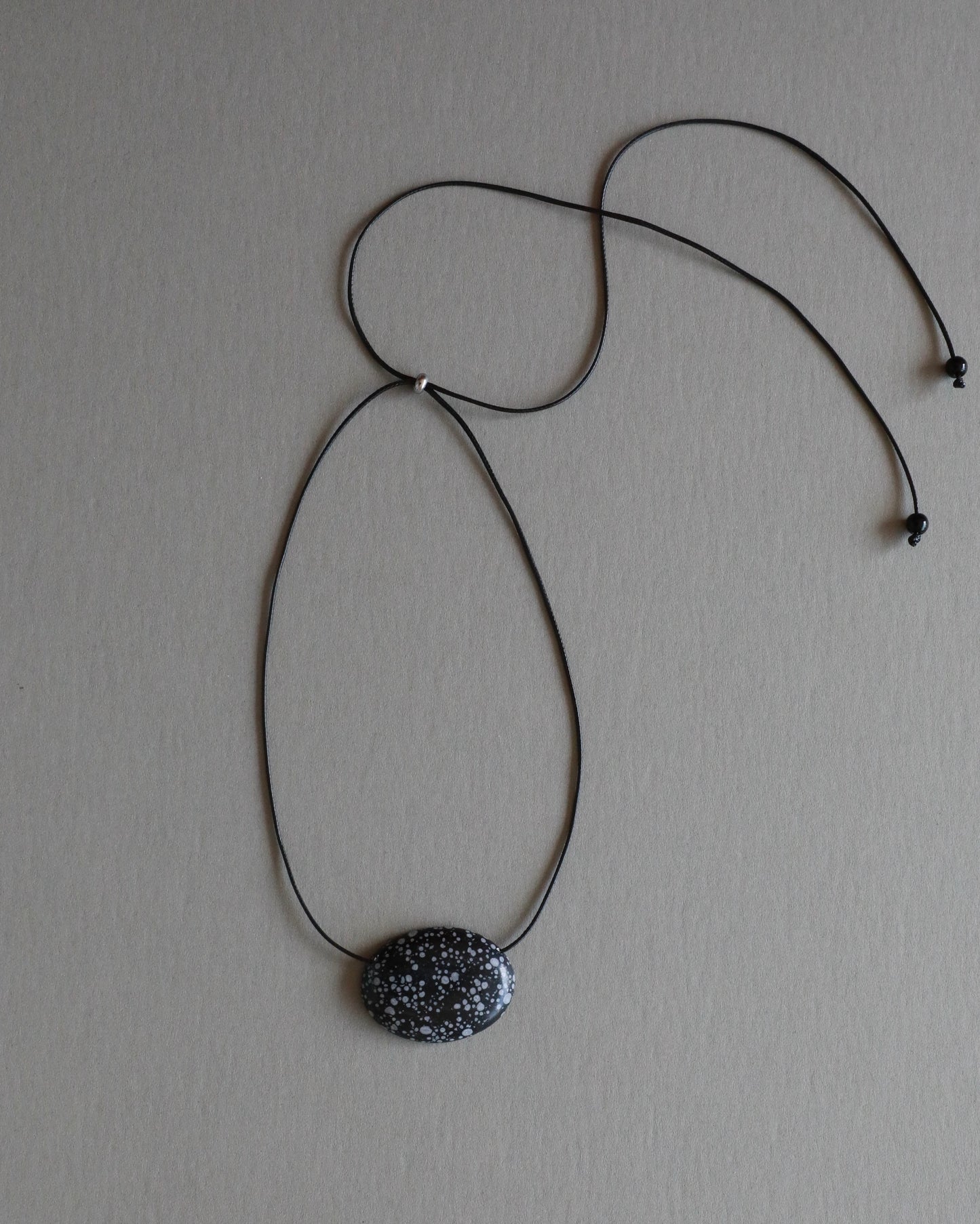 Super long snowflake obsidian pendant necklace with natural black and white speckled stone on adjustable black wax rope cord