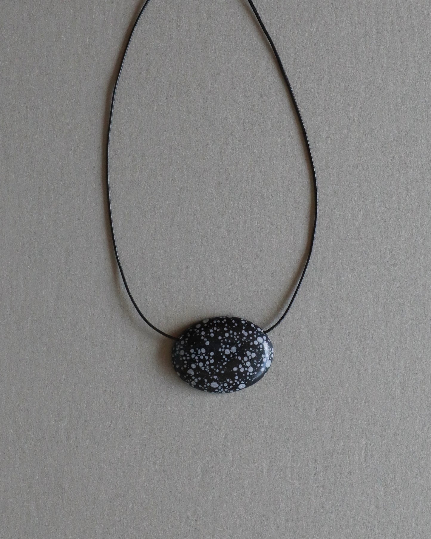 Super long snowflake obsidian pendant necklace with natural black and white speckled stone on adjustable black wax rope cord