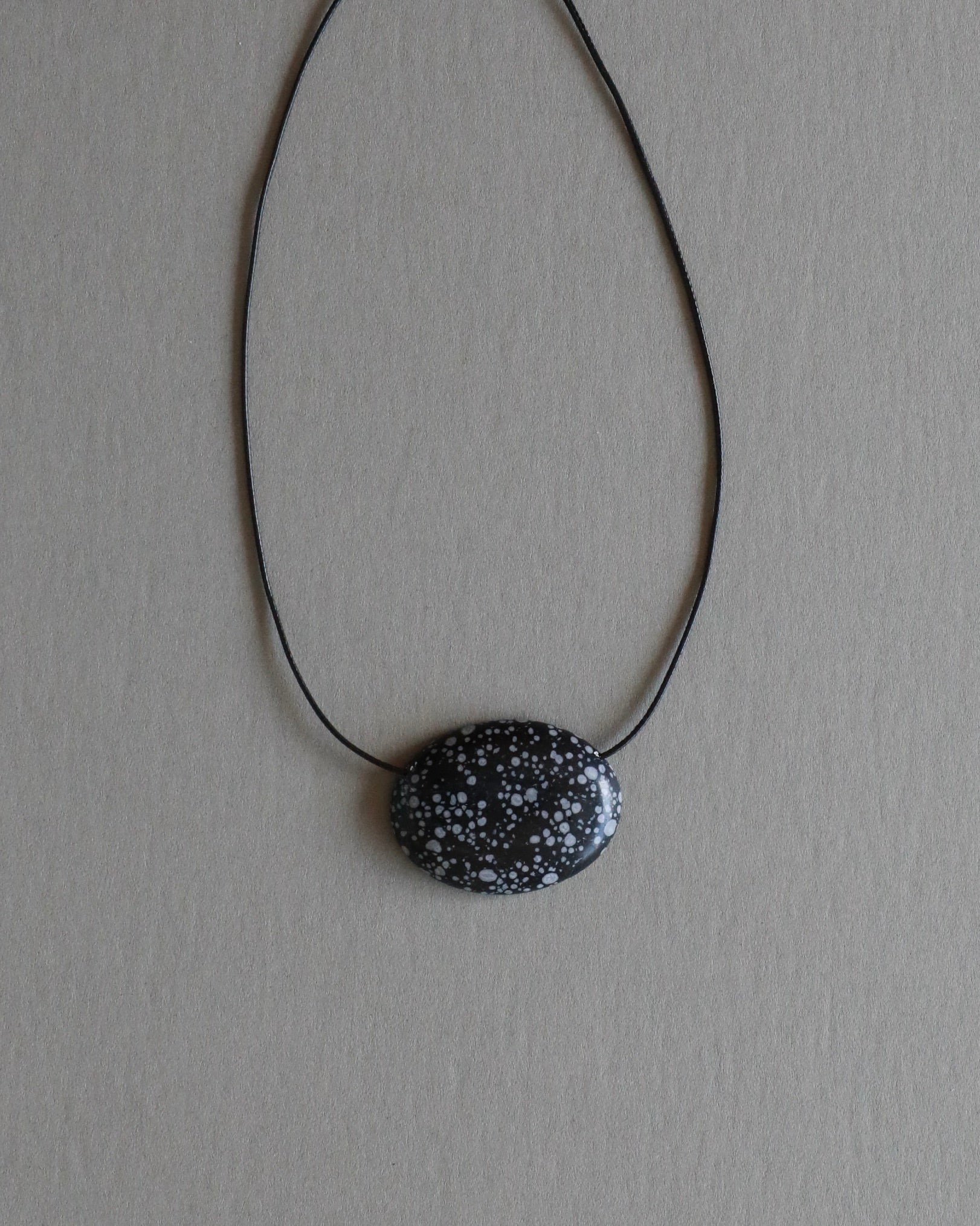 Super long snowflake obsidian pendant necklace with natural black and white speckled stone on adjustable black wax rope cord