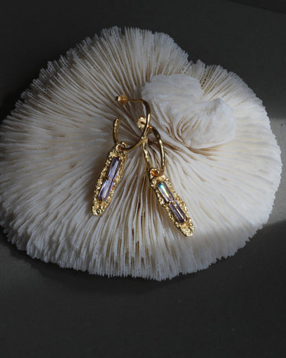 Twilight Gleam gold and purple zircon earrings styled on coral texture for jewelry photography