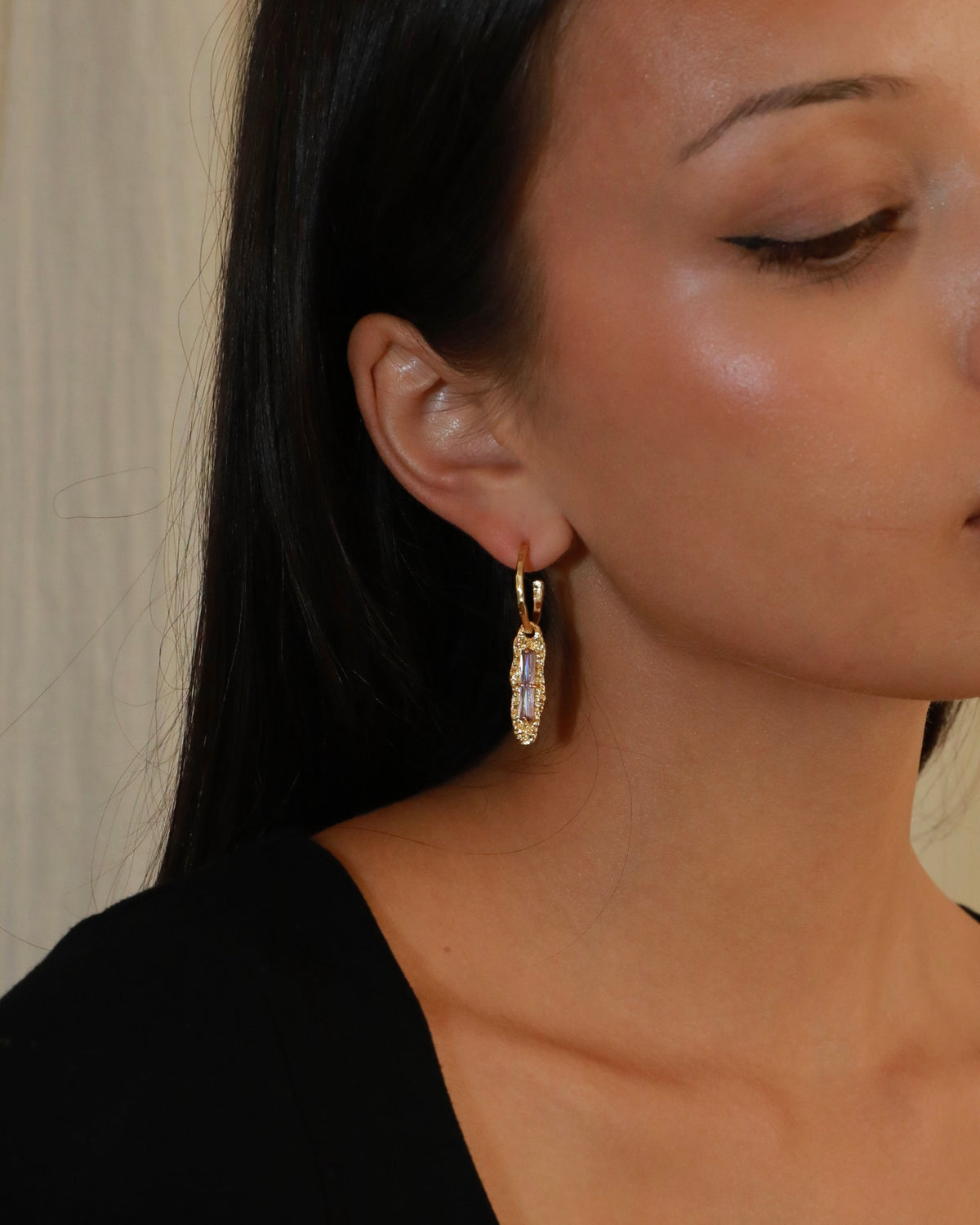 Twilight Gleam gold drop earrings with baguette-cut purple zircon stones, hammered organic pendants and polished gold hoops model