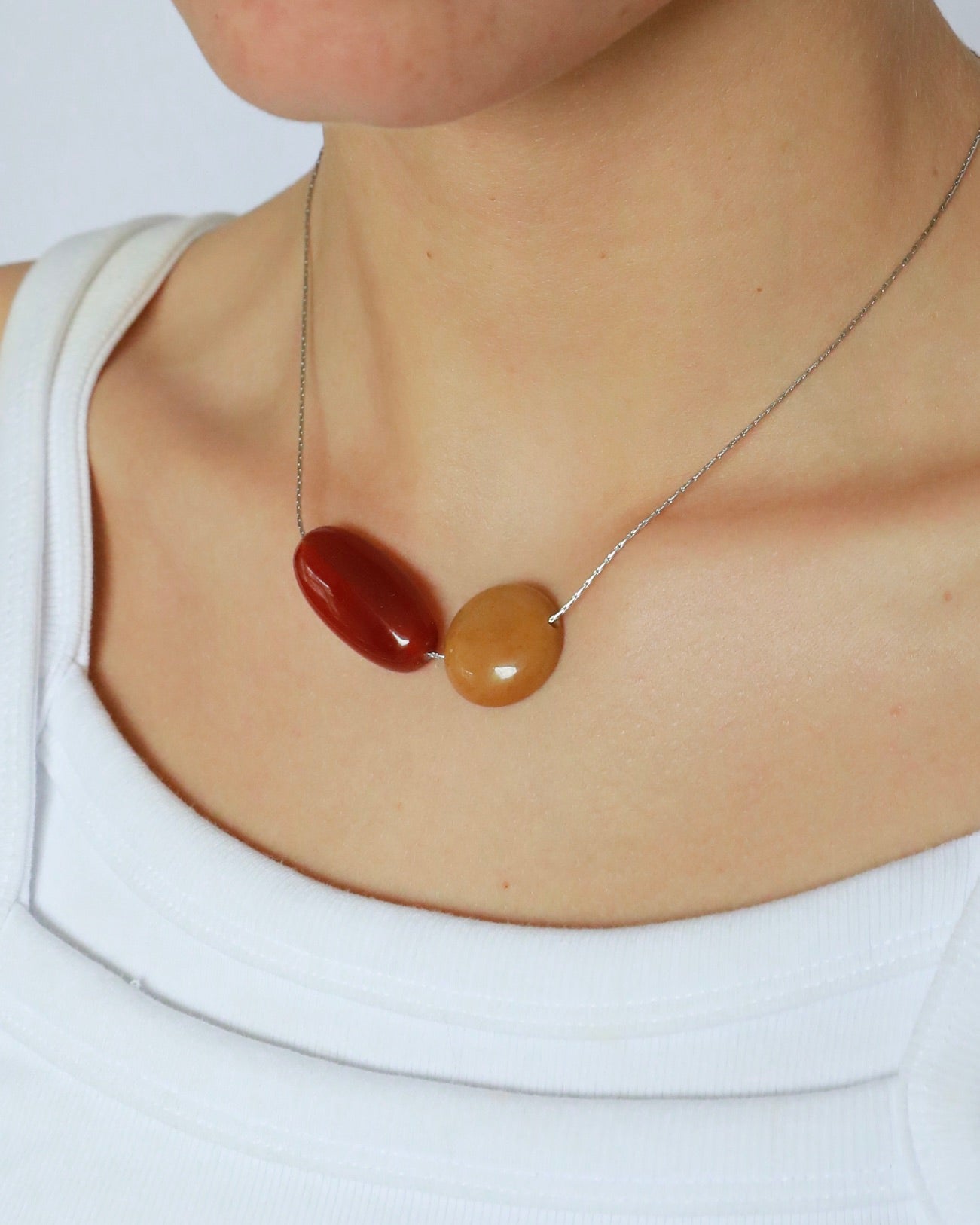 Necklace with two oval-shaped beads worn by a person on a white background